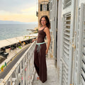 Teen girl wearing The Moment After Pants in espresso with a mint waistband and brown tank, on a seaside balcony in Europe